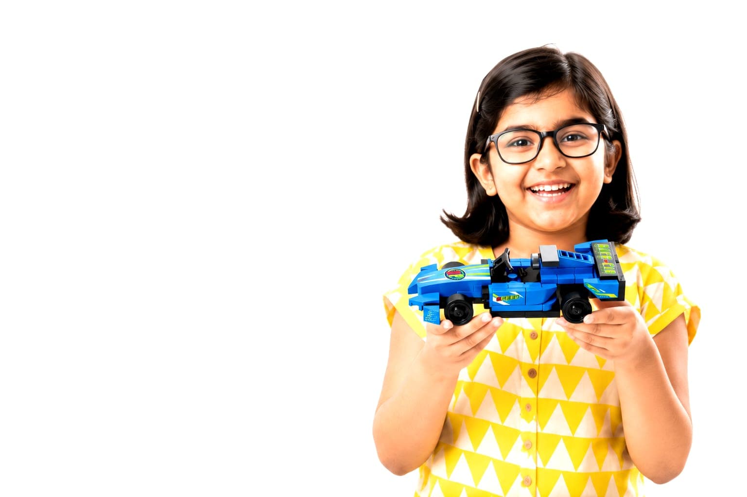 A girl proudly holding up her finished ThinkerPlace building-block race car