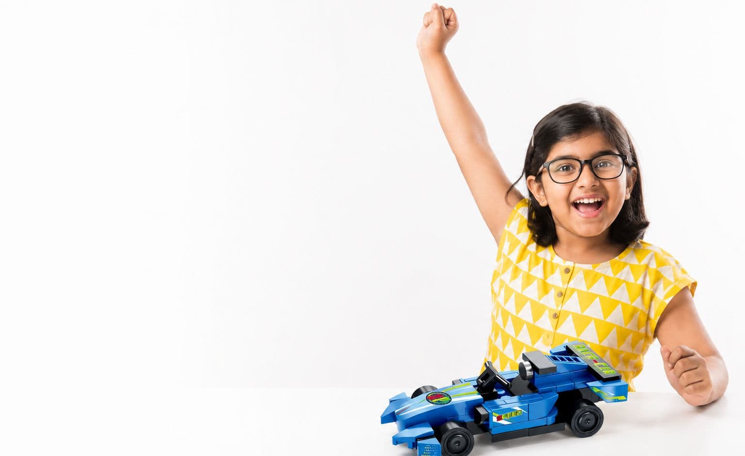 A child celebrating after building a ThinkerPlace building-block race car kit