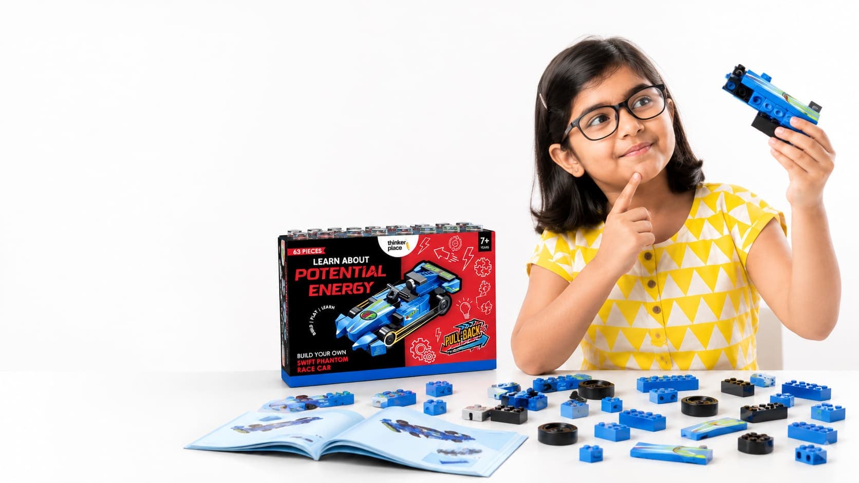 A girl thinking, holding a piece from a ThinkerPlace building-block race car kit
